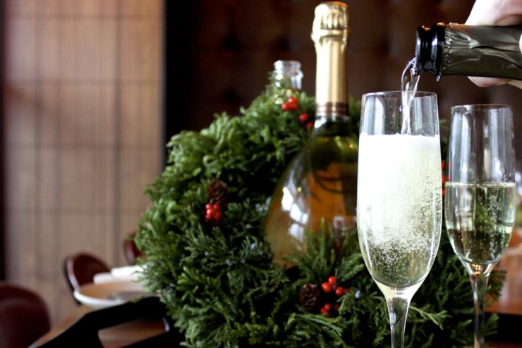 Champagne being poured into glass with bottle and wreath in background.