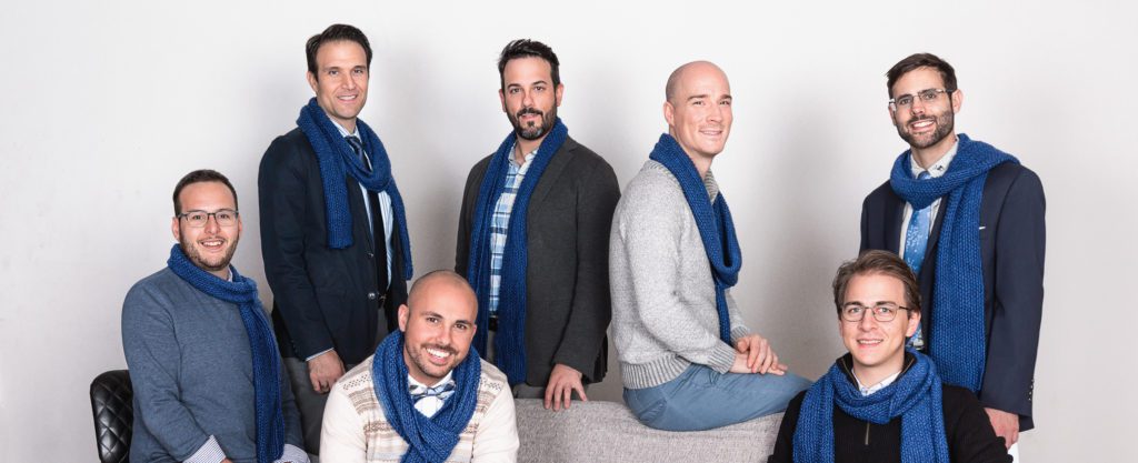 The 7 members of Men Singing Carols wearing blue scarves.
